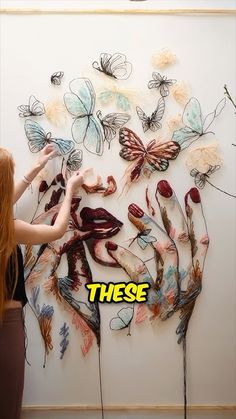 a woman standing in front of a wall with butterflies on it and the words these