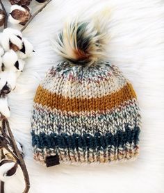 a multicolored knitted hat next to cotton flowers