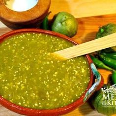 a wooden spoon in a bowl filled with green salsa