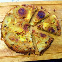 an onion pizza on a wooden cutting board