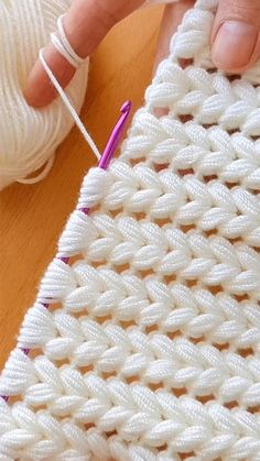 someone is knitting on a piece of white yarn