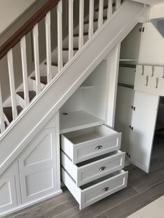 an under the stairs storage area with drawers and cupboards in white painted wooden flooring