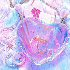 a pink heart shaped purse sitting on top of a fur covered floor next to other items