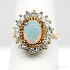 One 14k yellow gold ring containing one opal described above in a four-prong setting. The opal is surrounded by eighteen (18) prong set, round single cut diamonds described below: 18 = 0.54 ctw (Est.) SI2-11/G-H The ring weighs 4.26 grams. Size - 4.75 Appraised Value: $2,800.00 Independent Appraisal Included. Pictured boxes are not included. Shipping- Items will arrive carefully packed in a jewelry gift box, wrapped in bubble wrap, and shipped in a box via Priority Shipping with Signature Confir Vintage Diamond Opal Ring, Classic Multi-stone Opal Ring, Classic Yellow Gold Opal Ring With Center Stone, Vintage Diamond Opal Ring For Anniversary, Classic Opal Diamond Ring With Prong Setting, Classic Diamond Opal Ring With Prong Setting, Classic Round Cut Opal Ring, Formal Opal Ring With Prong Setting, Sister Jewelry