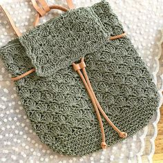 a green crocheted bag sitting on top of a white doily