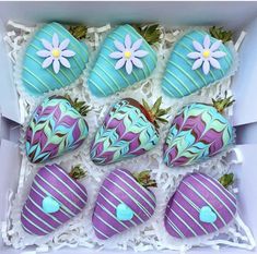 six decorated chocolate covered strawberries in a box with flowers and leaves on the top