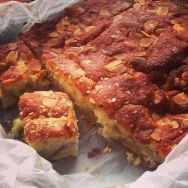 a piece of cake sitting on top of a pan covered in wax paper and some nuts