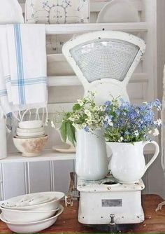 an old fashioned blender with blue flowers in it on a table next to plates and bowls