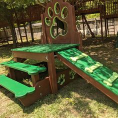 a wooden play set with a green slide and paw prints