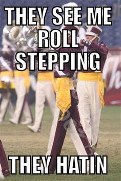 two men in maroon and yellow uniforms playing trombones on a field with the caption they see me roll stepping