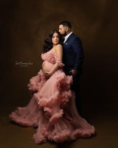 a pregnant woman in a pink dress and a man in a tuxedo pose