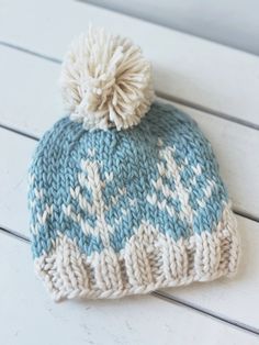 a blue and white knitted hat sitting on top of a wooden table