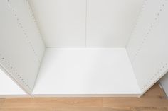 the corner of a room with white walls and wood flooring