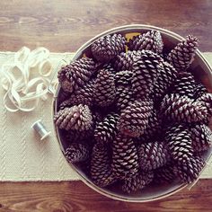 a bowl full of pine cones sitting on top of a table next to a string