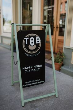 a happy hour sign on the sidewalk in front of a store