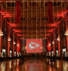 the inside of a building decorated with christmas lights and large red screen displaying a football team's logo