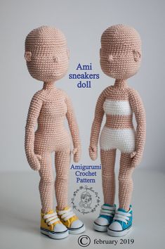 two crocheted dolls standing next to each other on top of a white surface