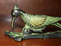 a green bird figurine sitting on top of a wooden table