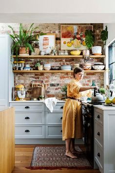 a woman in a yellow dress is standing at the kitchen counter and looking into the oven