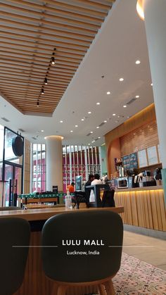 two chairs sitting in front of a counter with people standing at the bar behind them