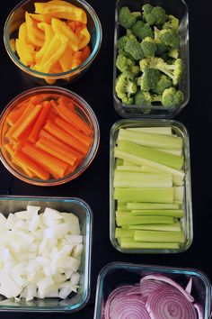 four containers filled with different types of vegetables next to each other on a black surface