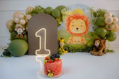 a birthday cake with the number one lit up in front of an animal themed backdrop