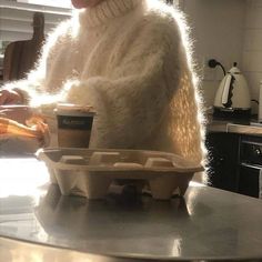 a woman sitting at a table with two cups in front of her