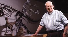 an older man standing in front of a display of dinosaurs