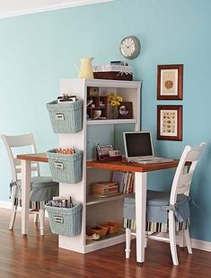 a room with a desk, chair and computer on it in front of a blue wall