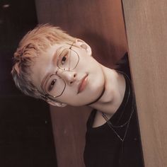 a young boy wearing glasses leaning against a wall