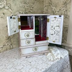 an old white dresser with red drawers sits on a table