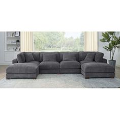 a large gray sectional couch sitting on top of a rug in front of a window