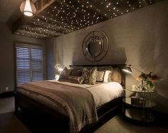 a bed room with a neatly made bed and lights on the ceiling above it's headboard