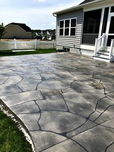 an outdoor patio with flagstone pavers and white picket fence in the back yard