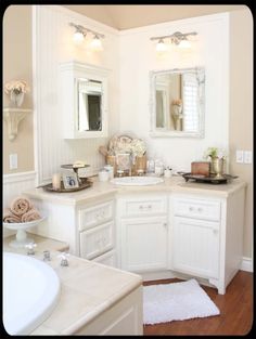 a white bathroom with two sinks, mirrors and other items on the counter top in front of it