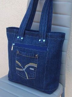 a denim purse with an embroidered pocket on the front and side, sitting on a chair