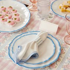 the table is set with pink and blue plates, napkins, and desserts