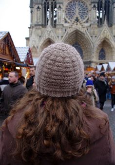 the back of a woman's head wearing a knitted hat at an outdoor market