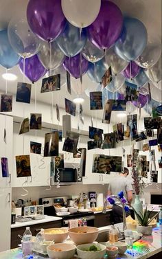 balloons and pictures hang from the ceiling above a counter in a kitchen with bowls on it