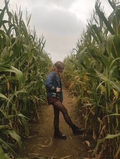 a woman standing in the middle of a corn field