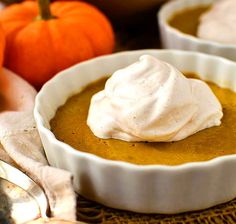 two white bowls filled with pumpkin pie and whipped cream