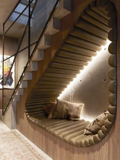 a curved staircase in the middle of a living room next to a couch with pillows on it