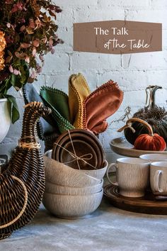 a table topped with bowls and cups filled with fall decorations