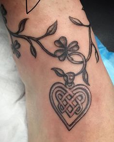 a tattoo on the leg of a woman with a heart and cross in it's center