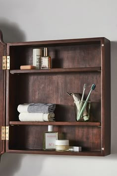 a wooden shelf with towels and other items on it, including a toothbrush holder