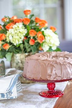 a chocolate cake sitting on top of a table next to a vase filled with flowers