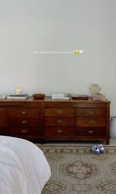 a bed sitting next to a wooden dresser on top of a rug