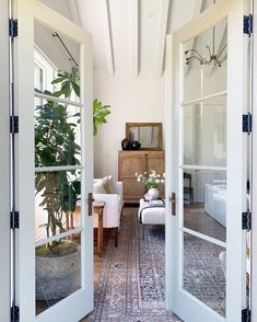 an open door leading to a living room filled with furniture and potted plants on top of a rug