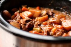 a pot filled with meat and carrots on top of a stove