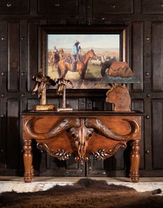 an old wooden table with a painting on the wall above it and a cowhide rug in front of it